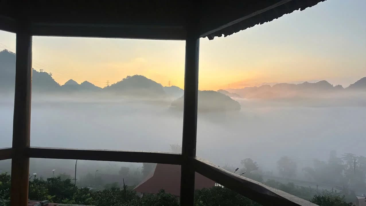 Mái hiên và lan can gỗ mở ra thung lũng phủ sương lúc bình minh