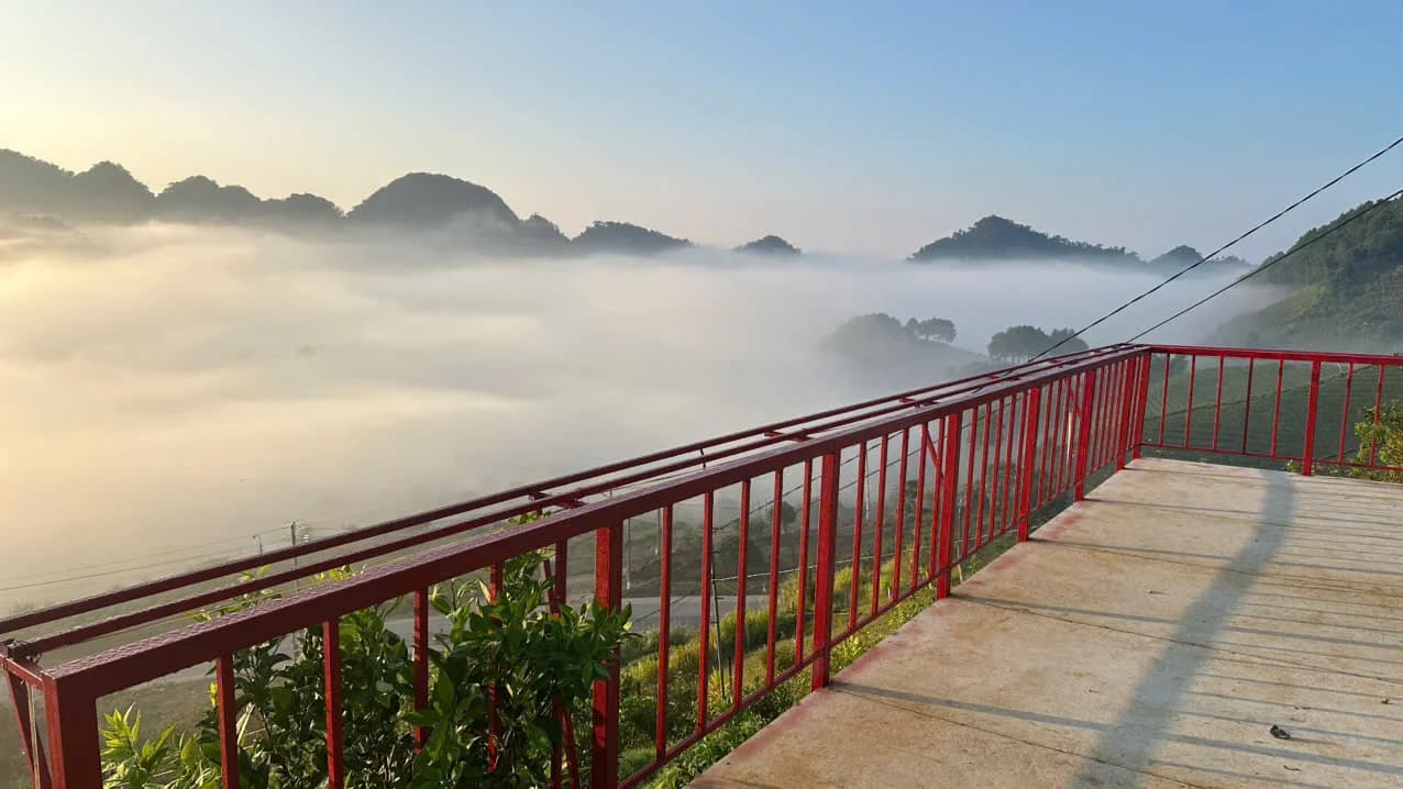 Sân hiên với lan can đỏ nhìn ra thung lũng phủ sương