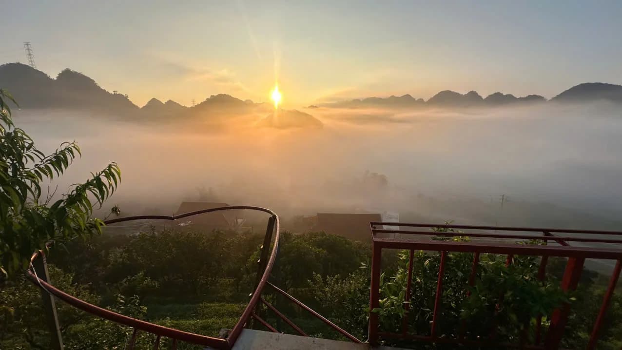 Mặt trời lên trên thung lũng phủ sương, phía trước là lan can hình trái tim